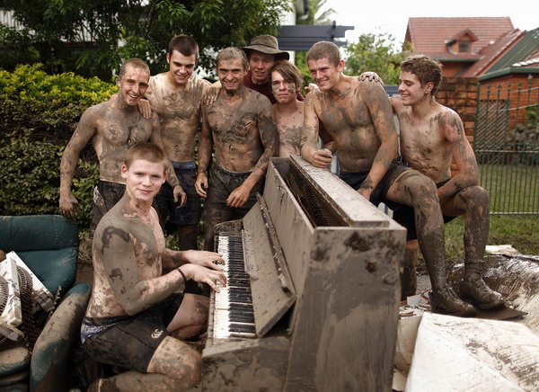 The mud covered friends of Andrew Taylor (2nd R), pose around a destroyed piano, as they help his family clean their house after flood waters receded in the Brisbane suburb of Westend January 14, 2011. Parts of Australia&apos;s third-largest city reopened Friday as deadly floodwaters that had swamped entire neighborhoods receded, revealing streets and thousands of homes covered in a thick layer of putrid sludge.[China Daily/Agemcies]