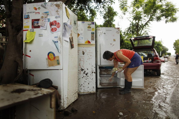 A woman removes produce from damaged refrigerators after flood waters receded in the Brisbane suburb of West End January 14, 2011. [China Daily/Agemcies]