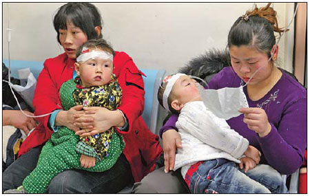 Two mothers hold their children as they receive intravenous drips in Beijing Children's Hospital on Friday. [Photo:Wang Jing / China Daily]