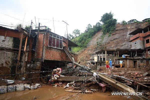 Villagers stand in front of the remains of their homes after a landslide in Nova Friburgo, Brazil, Jan. 15, 2011. According to the local government, the death toll caused by this week's heavy rains and mudslide that hit Brazil's Rio de Janeiro state has reached at least 550. (Xinhua/Agencia Estado)