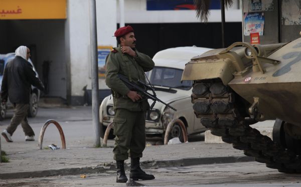 A member of the Tunisian national guard stands near a tank downtown in Tunis January 16, 2011. Soldiers and tanks were stationed in the centre of Tunis to restore order in the aftermath of looting that broke out when Zine al-Abidine Ben Ali, president for more than 23 years, fled to Saudi Arabia following a month of violent anti-government protests that claimed dozens of lives. [Xinhua]