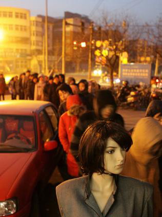 A mannequin stands in a line of people waiting to buy tickets home for the Spring Festival in a picture issued online on Jan 13. [Photo/tt.mop.com] 