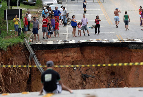 Local residents watch beside a flood-destroyed bridge in Rio de Janeiro, Brazil, Jan 16, 2011. Brazil rains and floods have killed at least 611 people as forecasts of more storms and fears of disease outbreaks overshadowed rescue operations. [Xinhua]