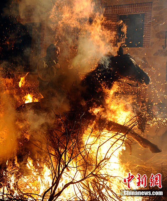 A man rides a horse through a bonfire on January 16, 2011 in the small village of San Bartolome de Pinares, Spain. In honor of San Anton, the patron saint of animals, horses are riden through the bonfires on the night before the official day of honoring animals in Spain. [Chinanews.com]