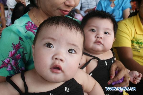A pair of twin brothers pose during the first similarity competition for multiple birth siblings in Yangon, Myanmar, on Jan. 16, 2011. The competition attracted a total of 101 pairs of contestants.[Xinhua]