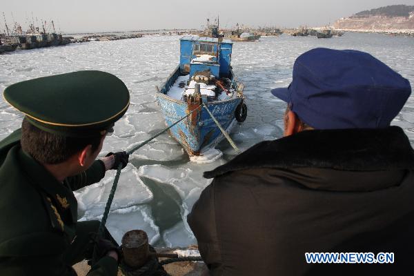 Soldiers help fishermen to tie boats at Zhifu Island in eastern China's Shandong Province, Jan. 17, 2011. The thickness of the freezing ice has amounted to 15 to 20 centimeters due to continuous cold waves while most offshore activities were forced to be halted. 