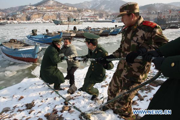 Soldiers help fishermen to tie boats at Zhifu Island in eastern China's Shandong Province, Jan. 17, 2011. The thickness of the freezing ice has amounted to 15 to 20 centimeters due to continuous cold waves while most offshore activities were forced to be halted. 