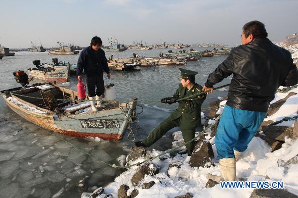 Soldiers help fishermen to tie boats at Zhifu Island in eastern China's Shandong Province, Jan. 17, 2011. The thickness of the freezing ice has amounted to 15 to 20 centimeters due to continuous cold waves while most offshore activities were forced to be halted. 