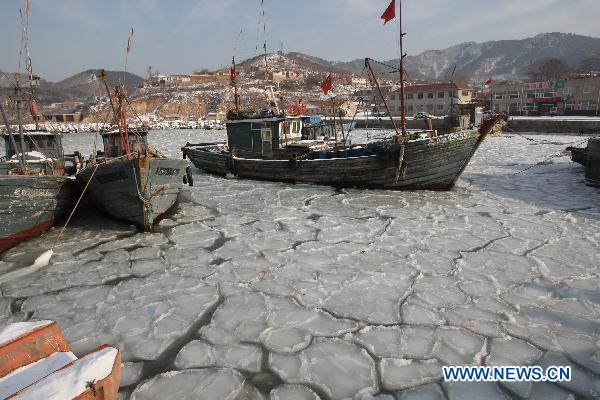 Fishing boats are seen stranded in the iced surface at Zhifu Island in eastern China's Shandong Province, Jan. 17, 2011. The thickness of the freezing ice has amounted to 15 to 20 centimeters due to continuous cold waves while most offshore activities were forced to be halted.