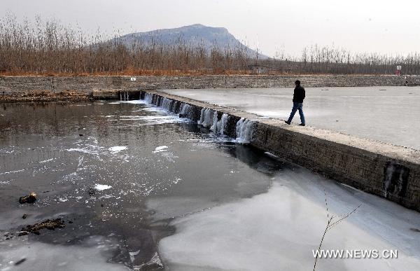 A man walks on a sluice in Shuangquan Township of Changqing, Jinan, capital of east China&apos;s Shandong Province, Jan. 18, 2011. A severe drought hit Shandong Province, covering an area of more than 20,106 square kilometers. Facing shortage of water, local government planned to invest 275 million yuan (about 41.7 million US dollars) to build a set of irrigation projects.