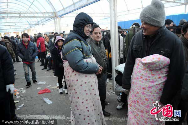 Migrant workers bundled up in quilts wait in line to buy train tickets at a station in Hangzhou, east China&apos;s Zhejiang province on Jan 17, 2011. [Photo/CFP]