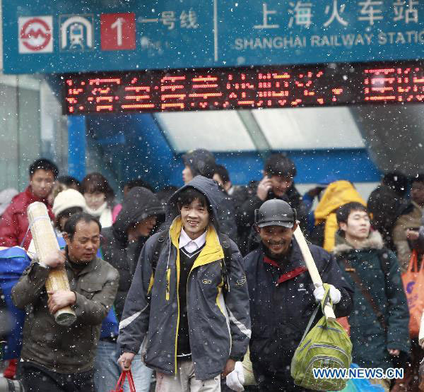 Passengers go to the railway station in snow in East China&apos;s Shanghai, Jan 18, 2011. [Xinhua] 