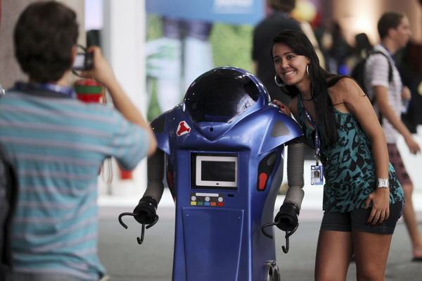 A participant poses next to a robot at the &apos;Campus Party&apos; Internet users gathering in Sao Paulo Jan 18, 2011. [China Daily/Agencies]