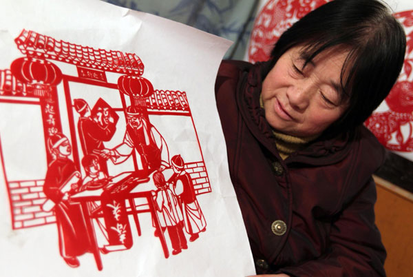 Paper cutting expert Wang Zhenzhu (R) from Yunchen city, North China's Shanxi province shows her creative work, Jan 18, 2011. [Photo/Xinhua] 