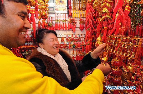 Indian businessman Amjed Khan (L) buys a golden abacus symbolizing good fortune in Yiwu Merchandise Market in east China's Zhejiang Province, Jan. 16, 2011. As the Chinese Spring Festival of the year of rabbit approaches, a variety of Spring Festival decorations including the plush rabbit toys and red Chinese lanterns were put on sale in the Yiwu Merchandise Market which attracted buyers both at home and abroad.