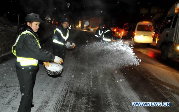 Road administration officials sprinkle salt on the frozen No. 308 Provincial Highway in Kaili, southwest China&apos;s Guizhou Province, Jan. 17, 2011. Snow and freezing rain hit the city of Kaili on Monday, trapping more than 2,000 vehicles in congestion. 