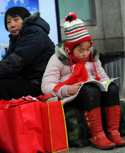 A child keeps reading during the time waiting for home at Beijing West Railway Station in Beijing, capital city of China, Jan 19, 2011. [Photo/Xinhua] 