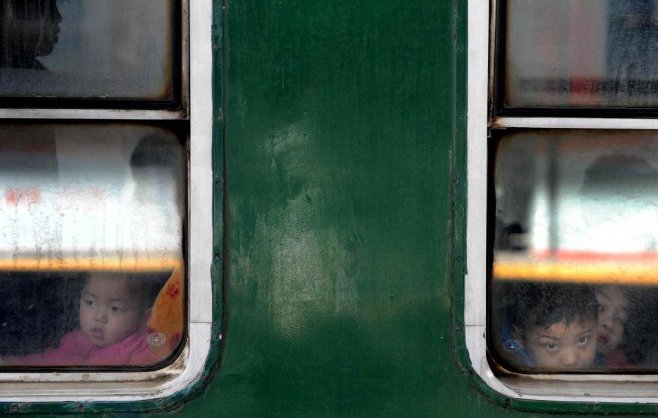 Children look out of the window of a train after boarding in Tianjin, Jan 19, 2011. [Photo/Xinhua]