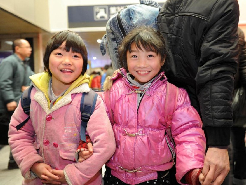 Sisters look happy as they wait to go home with their parents at Hangzhou railway station in Hangzhou, capital city of East China&apos;s Zhejiang province, Jan 17, 2011. [Photo/Xinhua]