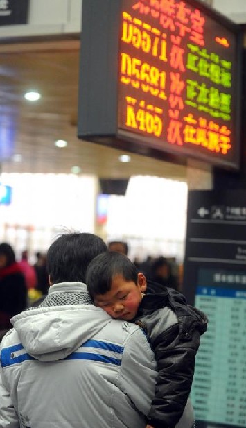 Holding his baby in arms, a man waits in line to buy tickets home at Shanghai railway station in Shanghai, East China, Jan 10, 2011. [Photo/Xinhua]