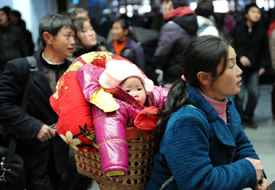 A woman carries her child in a basket while waiting to head for home at Hangzhou railway station in Hangzhou, capital city of East China&apos;s Zhejiang province, Jan 17, 2011. [Photo/Xinhua]