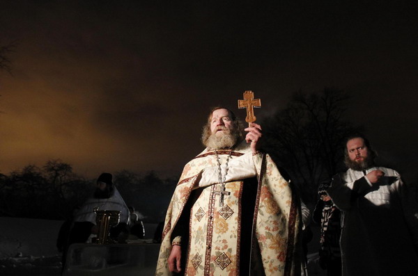 An Orthodox priest leads an Epiphany day celebration, with air temperature at about minus 16 degrees celsius in Moscow January 19, 2011. [China Daily/Agencies]