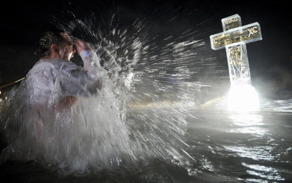 A man bathes in the icy waters of a pond during Epiphany celebrations in Nakhabino near Moscow January 19, 2011. [China Daily/Agencies]