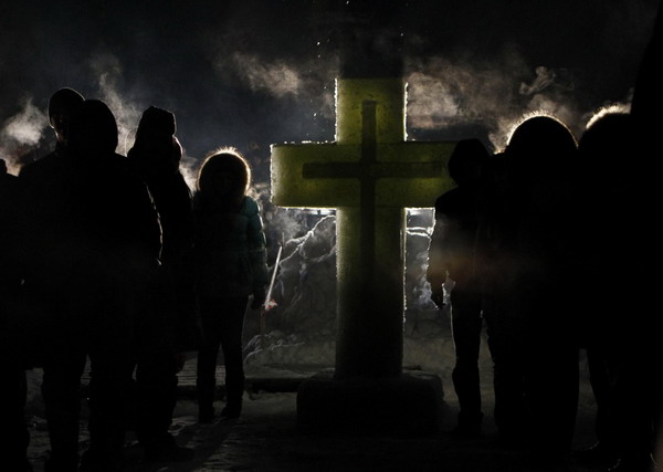 People stand around an ice hole at a pond during Orthodox Epiphany celebrations in the village of Velikoye, some 220 km (137 miles) north-east of Moscow January 18, 2011. [China Daily/Agencies]