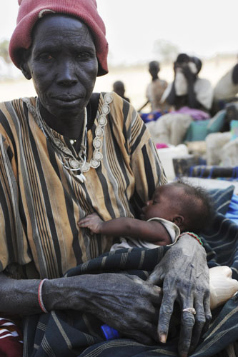 A woman holds her child after she and other newly arrived southern Sudanese returnees from Darfur are dropped off from a bus in Wanjok, near Aweil in Northern Bhar El-Ghazal January 16, 2011. [Xinhua/Reuters]