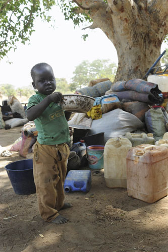 A newly arrived southern Sudanese child returnee from Darfur drinks water from a bowl shortly after being dropped off from a bus in Wanjok, near Aweil in Northern Bhar El-Ghazal January 16, 2011. [Xinhua/Reuters]