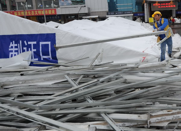 Construction workers clean up a snow-crushed roof at Guiyang Railway Station, Guiyang, capital of Southwest China&apos;s Guizhou province on Jan 19, 2011. Heavy snowfall crushed the roof of temporary ticket stalls at the station, resulting in two injuries and a slowdown in the ticket checking operation. Clean-up work is under way. [Photo/Xinhua]