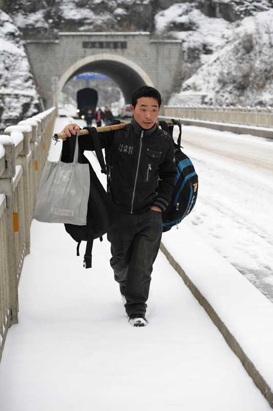 A migrant worker slogs through a section of the 319 National Highway, which runs from Xiamen to Chengdu, Jan 19, 2011. Due to heavy snow, long-distance inter-provincial buses stopped operation on the 319 National Highway, prompting 15 stranded migrant workers to walk back home for their Spring Festival reunion. [Photo/Xinhua] 