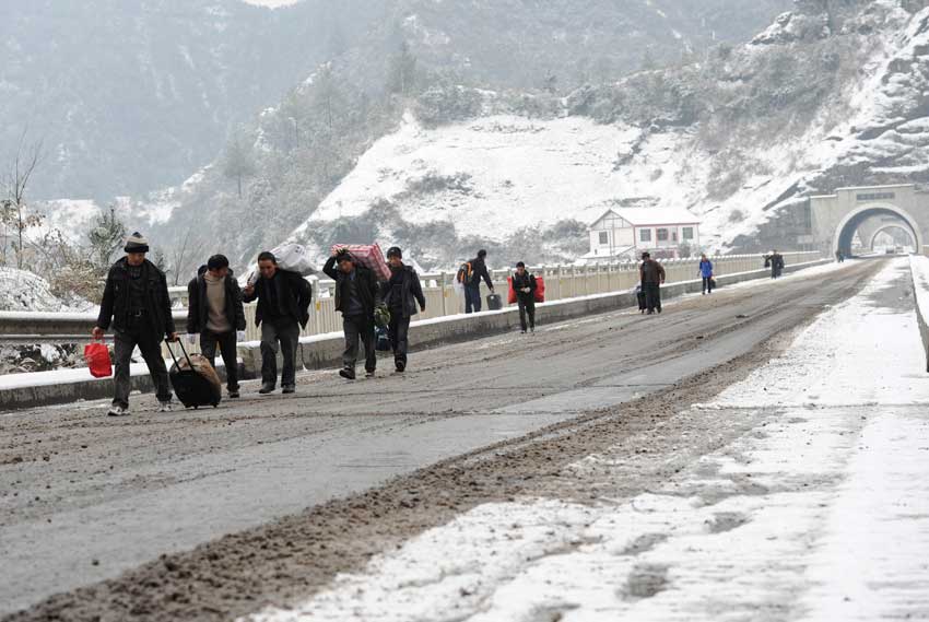 Migrant workers walk along a snow-covered section of the 319 National Highway, which runs from Xiamen to Chengdu, Jan 19, 2011. The highway was closed on Wednesday due to heavy snow, forcing home-bound migrant workers to start making the final 100 kilometers of their trip on foot. They trekked 4.5 hours through snow before getting on another bus.[Photo/Xinhua]