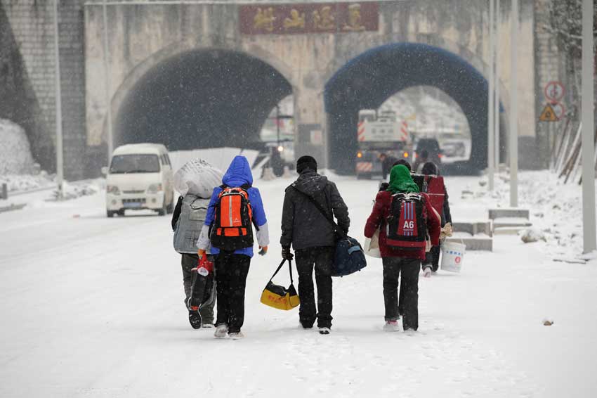 Migrant workers walk along a snow-covered section of the 319 National Highway, which runs from Xiamen to Chengdu, Jan 19, 2011. The highway was closed on Wednesday due to heavy snow, forcing home-bound migrant workers to start making the final 100 kilometers of their trip on foot. They trekked 4.5 hours through snow before getting on another bus.[Photo/Xinhua]