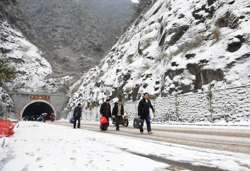 Migrant workers walk along a snow-covered section of the 319 National Highway, which runs from Xiamen to Chengdu, Jan 19, 2011. The highway was closed on Wednesday due to heavy snow, forcing home-bound migrant workers to start making the final 100 kilometers of their trip on foot. They trekked 4.5 hours through snow before getting on another bus.[Photo/Xinhua]