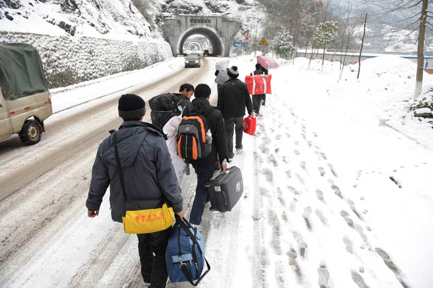 Migrant workers walk along a snow-covered section of the 319 National Highway, which runs from Xiamen to Chengdu, Jan 19, 2011. The highway was closed on Wednesday due to heavy snow, forcing home-bound migrant workers to start making the final 100 kilometers of their trip on foot. They trekked 4.5 hours through snow before getting on another bus.[Photo/Xinhua]