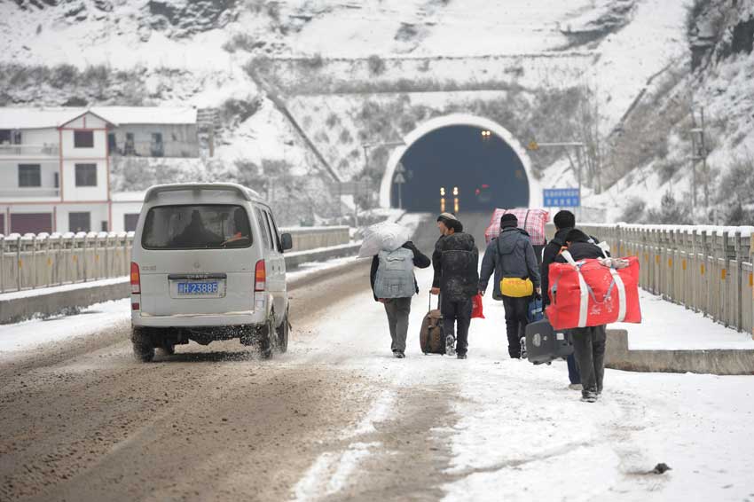 Migrant workers walk along a snow-covered section of the 319 National Highway, which runs from Xiamen to Chengdu, Jan 19, 2011. The highway was closed on Wednesday due to heavy snow, forcing home-bound migrant workers to start making the final 100 kilometers of their trip on foot. They trekked 4.5 hours through snow before getting on another bus.[Photo/Xinhua]