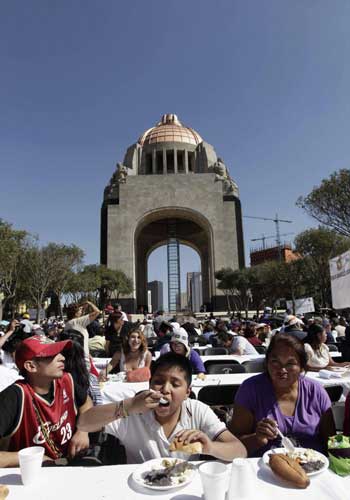 People receive free food as part of the &apos;Comedor Popular&apos; program by Mexico City&apos;s authorities at the Monument of the Revolution in Mexico City, Jan 19, 2011. At least 3,000 people received food, as part of the program, which aims to help the poor, children and the elderly affected by the current economic crisis, according to city government sources. [China Daily/Agencies]