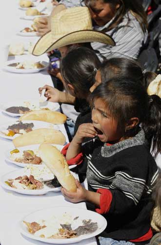 A child (front) eats free food as part of the &apos;Comedor Popular&apos; program by Mexico City&apos;s authorities at the Monument of the Revolution in Mexico City, Jan 19, 2011. [China Daily/Agencies]