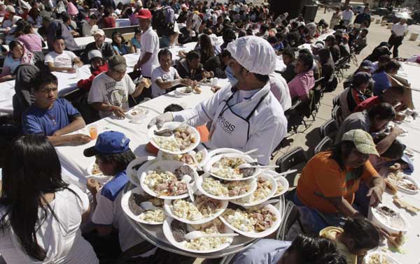 A man distributes free food as part of the &apos;Comedor Popular&apos; program by Mexico City&apos;s authorities at the Monument of the Revolution in Mexico City, Jan 19, 2011. [China Daily/Agencies]