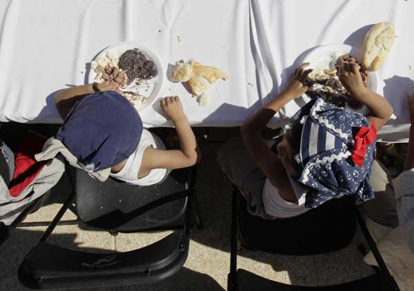 Children eat free food as part of the &apos;Comedor Popular&apos; program by Mexico City&apos;s authorities at the Monument of the Revolution in Mexico City, Jan 19, 2011. [China Daily/Agencies]