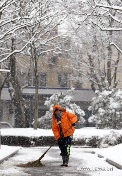 A cleaner sweeps the snow on a road in Shanghai, east China, Jan. 20, 2011. Local weather station issued warnings on the possible further snow storm.