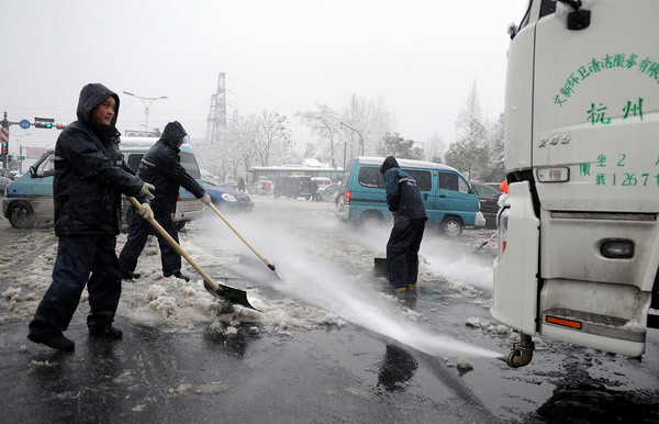 Sanitation workers clean snow off the road in Hangzhou, Jan 20, 2011. [Photo/Xinhua] 