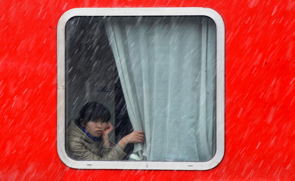 A woman looks out at sleet from a train about to depart Hangzhou, Jan 19, 2011. [Photo/Xinhua]