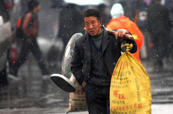 A man carries his luggage to a train station amid snow in Hangzhou, Jan 19, 2011. [Photo/Xinhua]