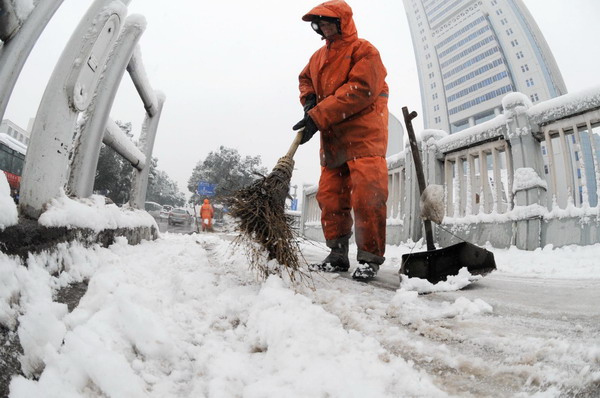 Sanitation workers clean snow off the roadside in Changsha, Central China&apos;s Hunan province, Jan 19, 2011. [Photo/Xinhua]