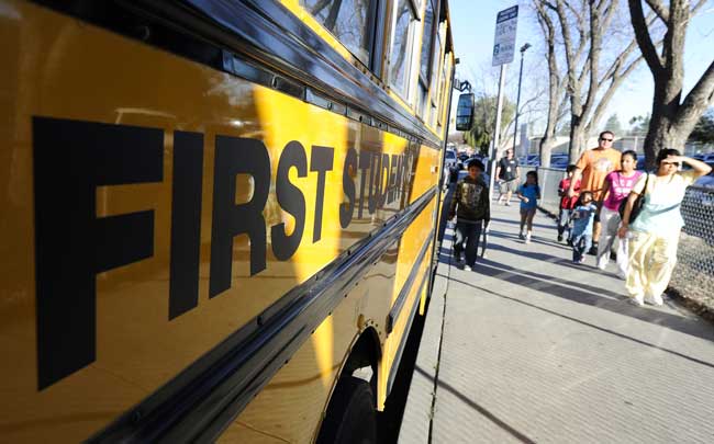 Family members of the students walk past a school bus near the gunshot site in Woodland Hills near Los Angeles, U.S., Jan. 19, 2011. A school police officer on Wednesday was shot and wounded on the campus of El Camino Real High School in Woodland Hills, about 40 km northwest of downtown Los Angeles, local media reported. [Xinhua]