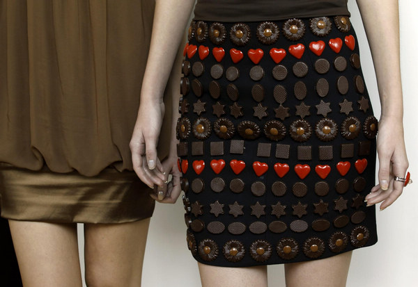 A model (R) wears a skirt adorned with chocolates made by Italian chocolatier Mirco Della Vecchia, during an exhibition in Hong Kong Jan20, 2011. [China Daily/Agencies] 