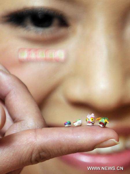 A model demonstrates mini shoes in Hong Kong, south China, Jan. 20, 2011. Thirty-five pairs of mini shoes were displayed in Hong Kong Thursday including the world&apos;s smallest pair that measured 3.8 millimeters long, 1.8 millimeters wide and 2.2 millimeters high. [Xinhua]