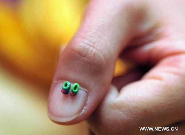 A model demonstrates the pair of world&apos;s smallest shoes by Guinness World Record in Hong Kong, south China, Jan. 20, 2011. Thirty-five pairs of mini shoes were displayed in Hong Kong Thursday including the world&apos;s smallest pair that measured 3.8 millimeters long, 1.8 millimeters wide and 2.2 millimeters high. [Xinhua] 